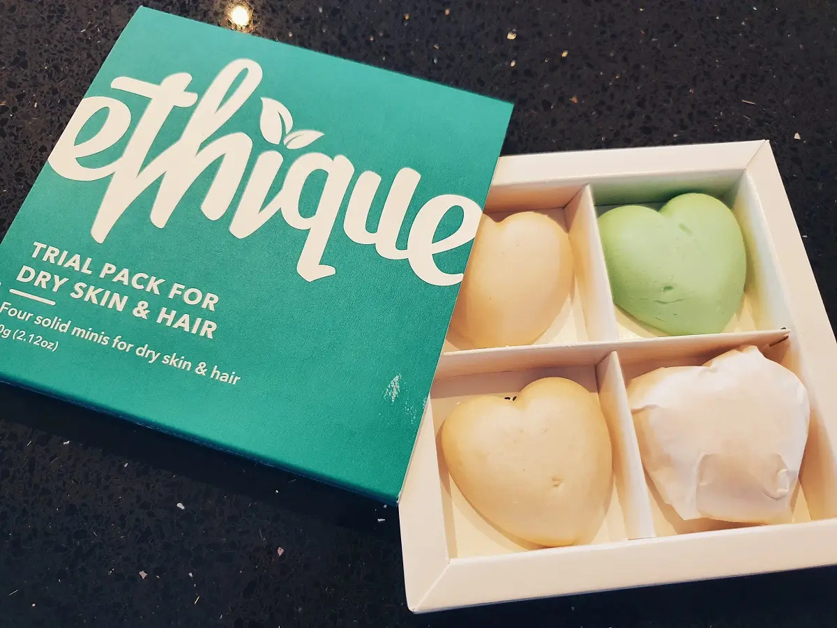 Four heart shaped mini solid shampoo bars in a cardboard container.