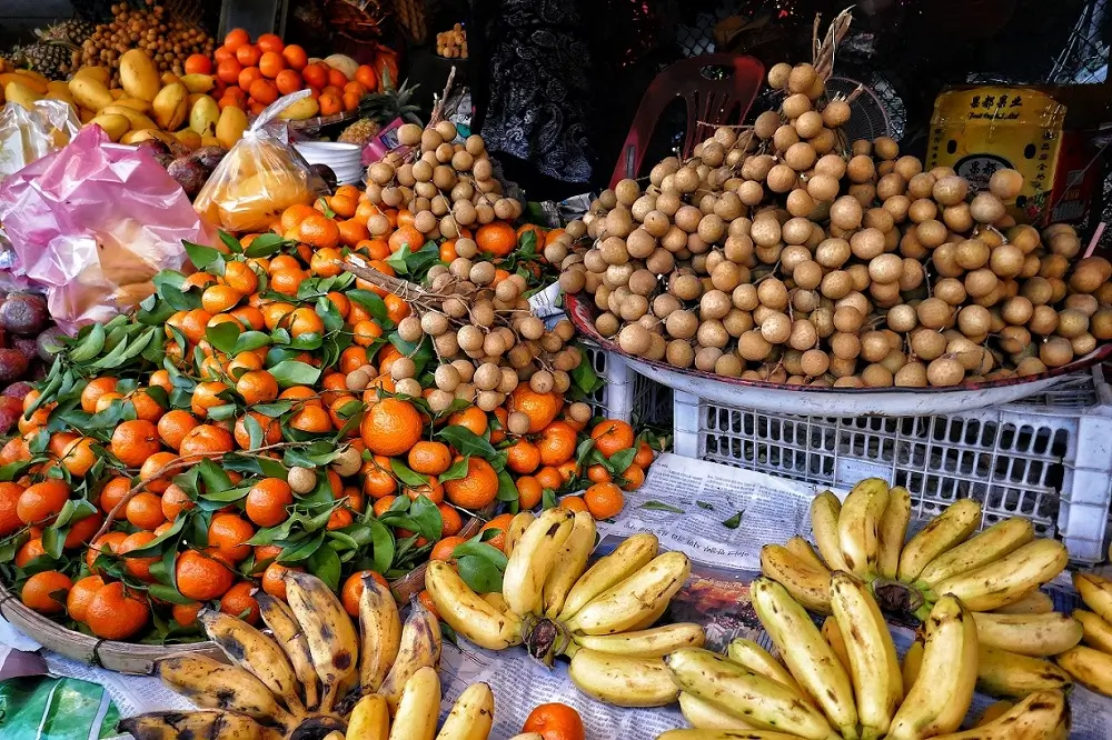 Various fruits and vegetables for sale at a market stall in Mexico including bananas, oranges, tomatoes and mangos.