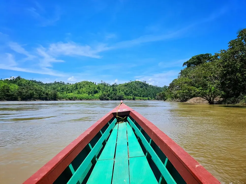 Red and green wood of the front of a boat sailing along the river border between Mexico and Guatemala.
