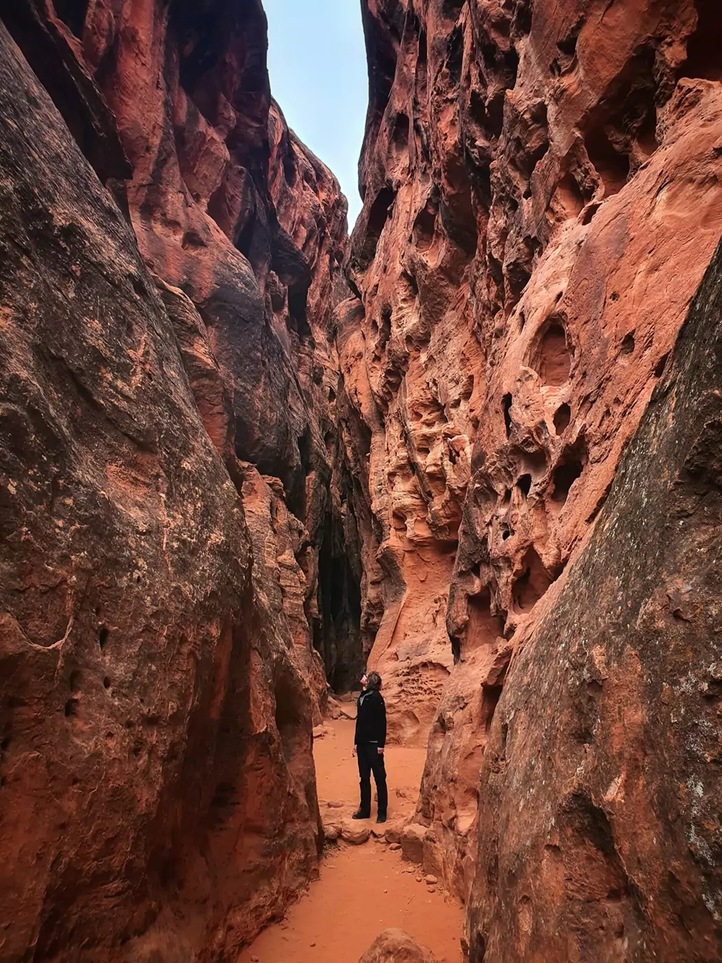 A person walking along the base of a slot canyon in Snow Canyon State Park.