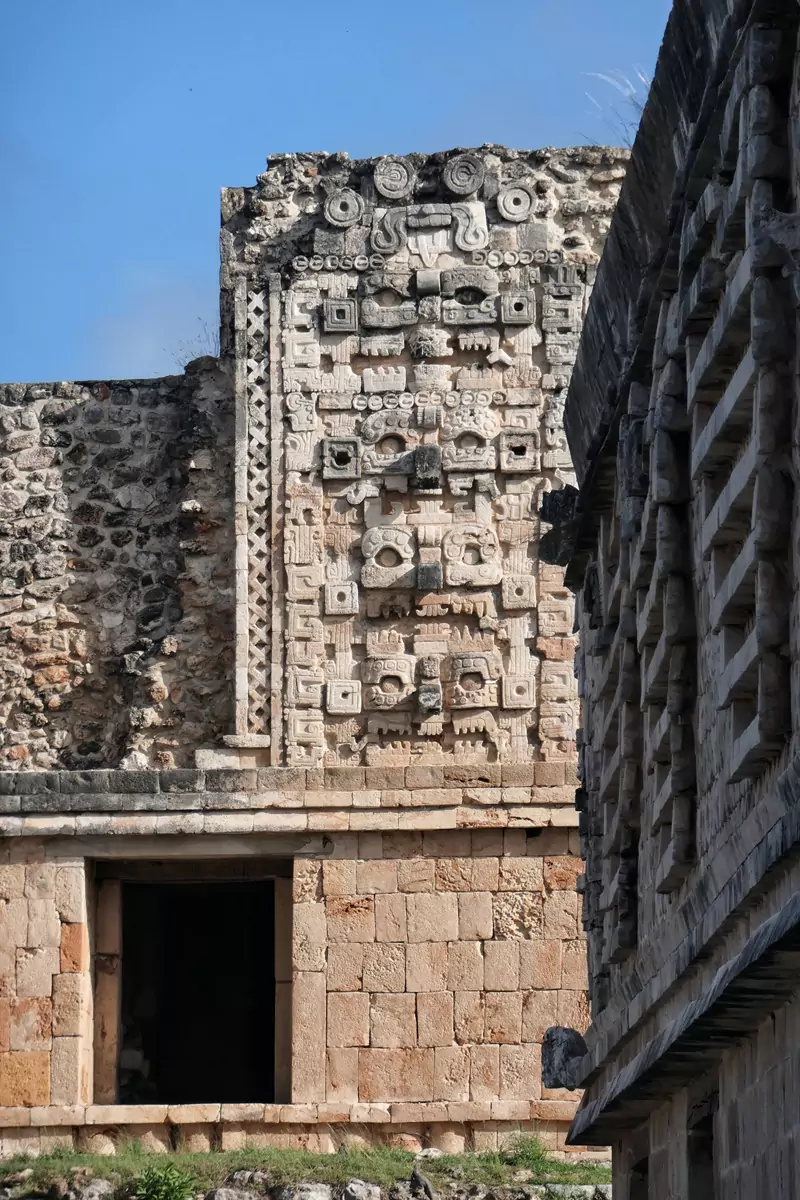 Intricate stone carvings on the façade of a building at Uxmal, representing faces with bared teeth.