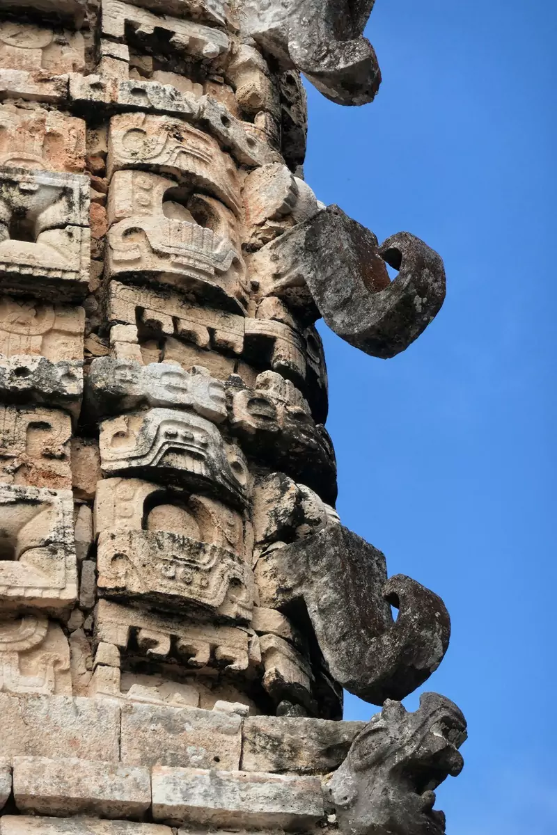 Intricate carvings into stone, featuring on the façade of a building in the ancient ruins of Uxmal.