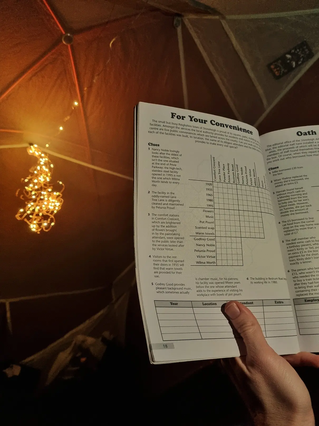 A puzzle book used for evening entertainment in a tent with fairy lights hanging in the background for lighting.