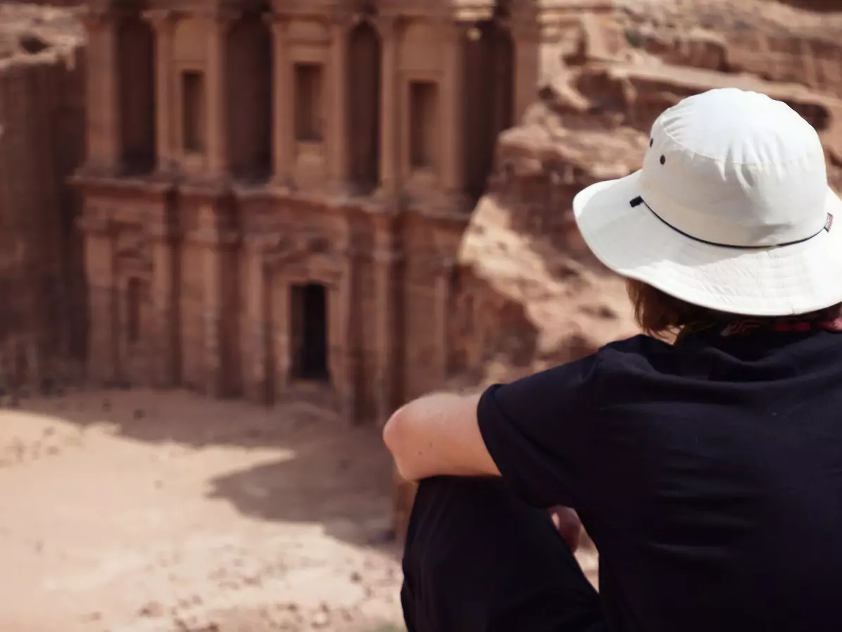 A man sitting at an overlook looking down at the Treasury at Petra.