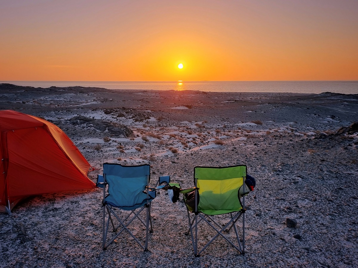 Oman Road trip sunset with two coloured folding chairs by an orange tent