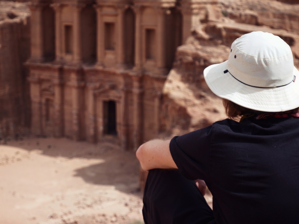 A man sitting at an overlook looking down at the Treasury at Petra