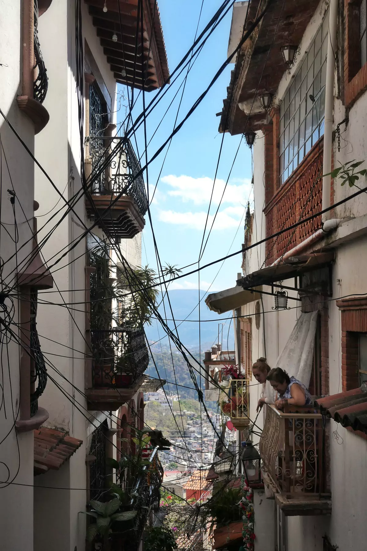 Residents on the steep streets of Taxco, chatting with a neighbour below their balcony.