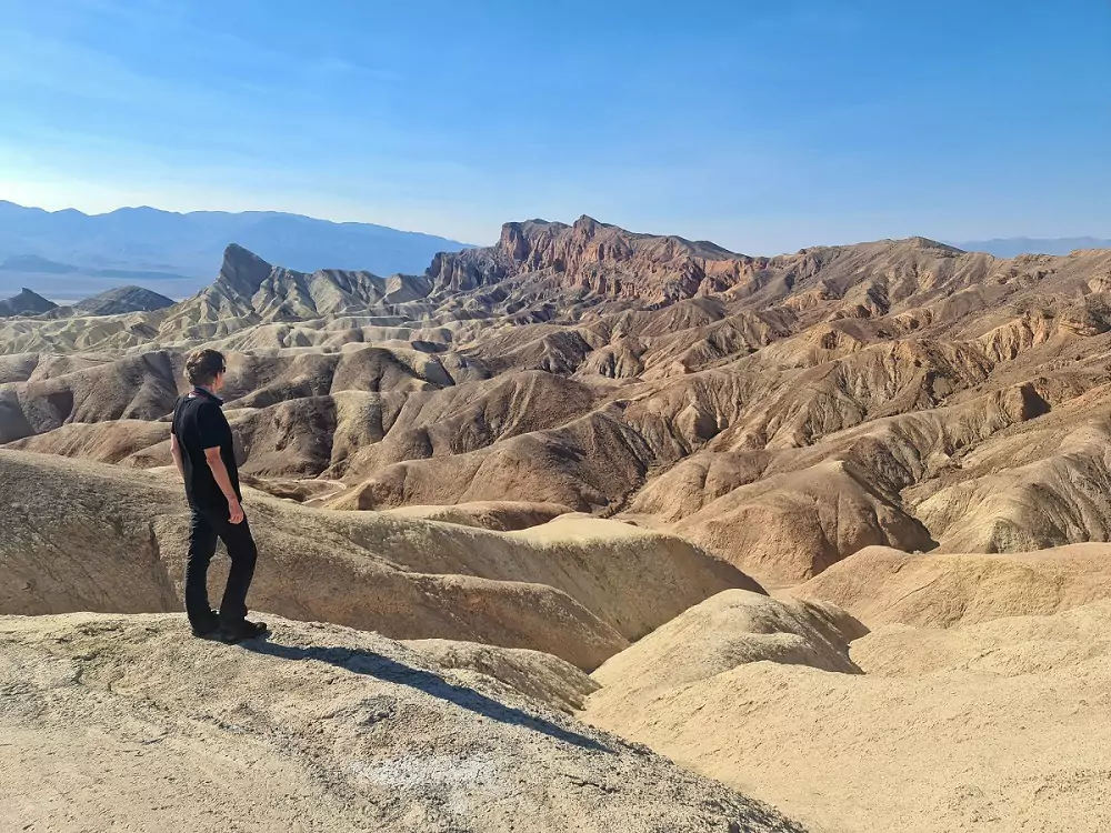 A person standing above crags at Death Valley as part of a California road trip.