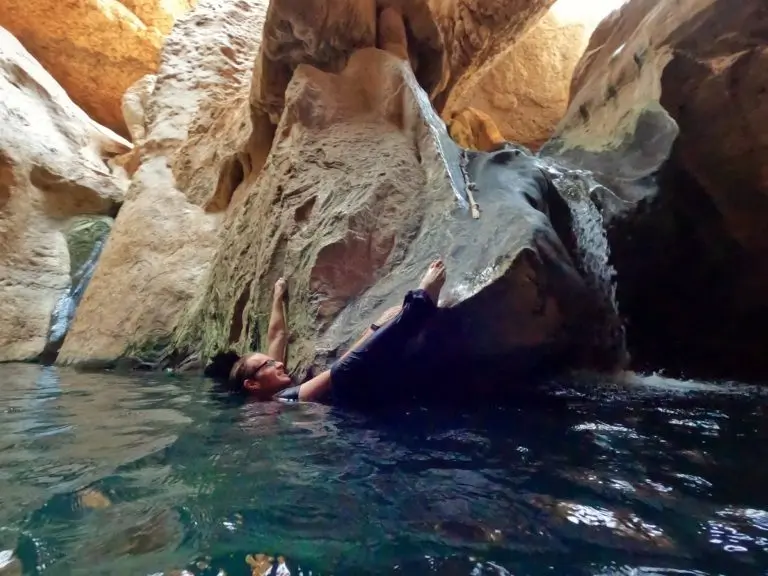 A person in the water trying to grab a rope in the secret cave at Wadi Shab.