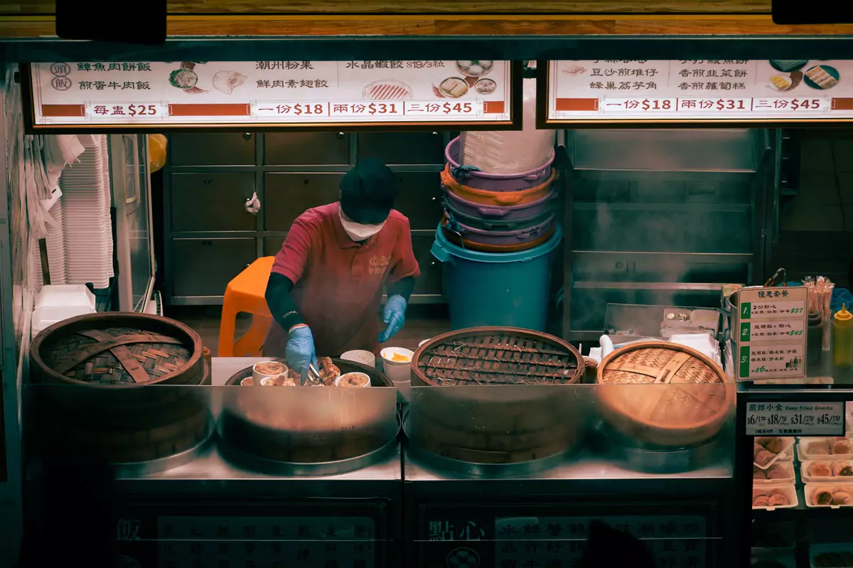A late-night food vendor tending to their stock in bamboo steamers in Mongkok, Hong Kong.