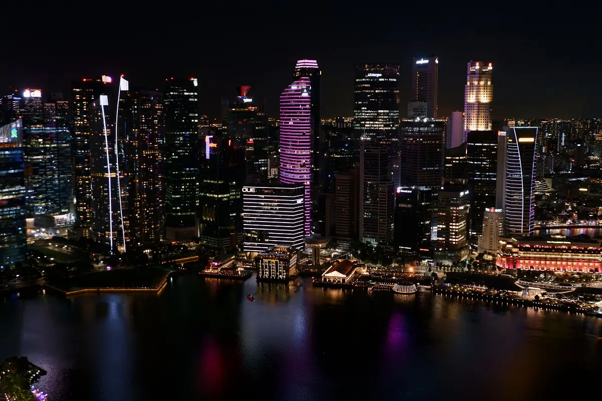 The waterfront and buildings lit up at night below Marina Bay Sands