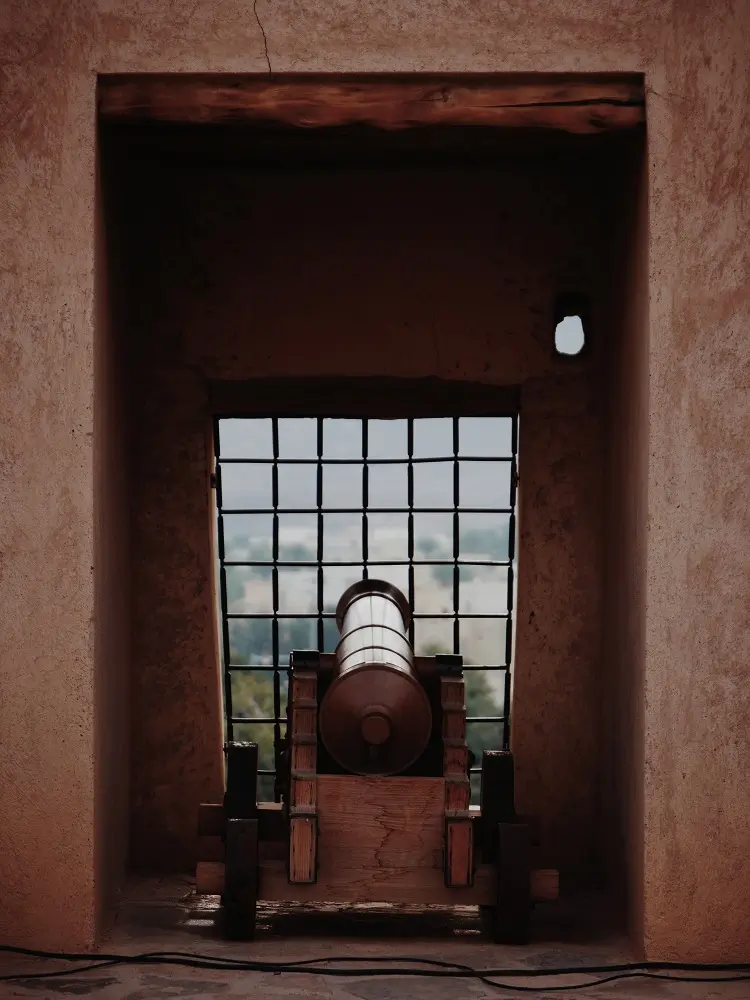 A canon pointing through a window at Nizwa fort, one of the best places to visit in Nizwa