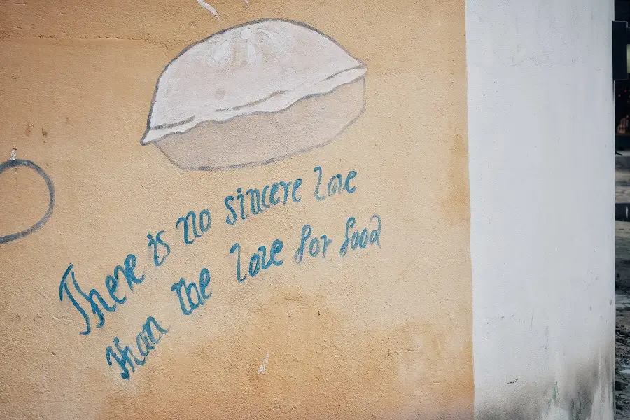 An advertising slogan on a wall stating 'There is no sincere love than the love for food'