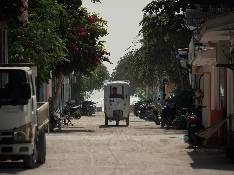 A delivery driver in a white tuk tuk in Maafushi, an island in the Maldives.
