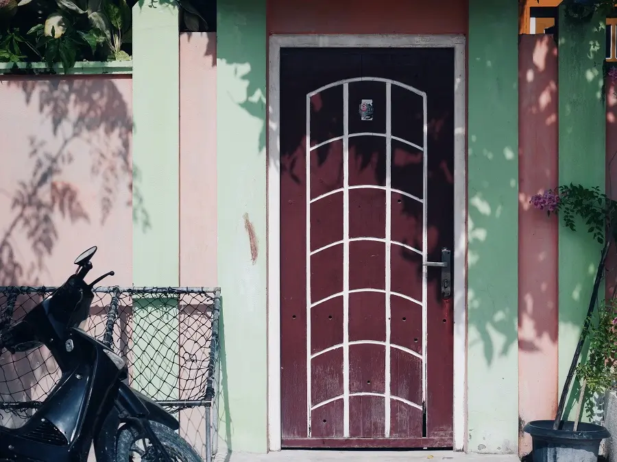 A red door with a curved design outside a house on the Maldives island of Maafushi.
