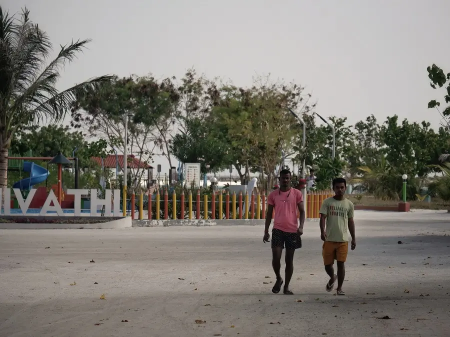 Two people walking along the street in Maafushi, an island in the Maldives.