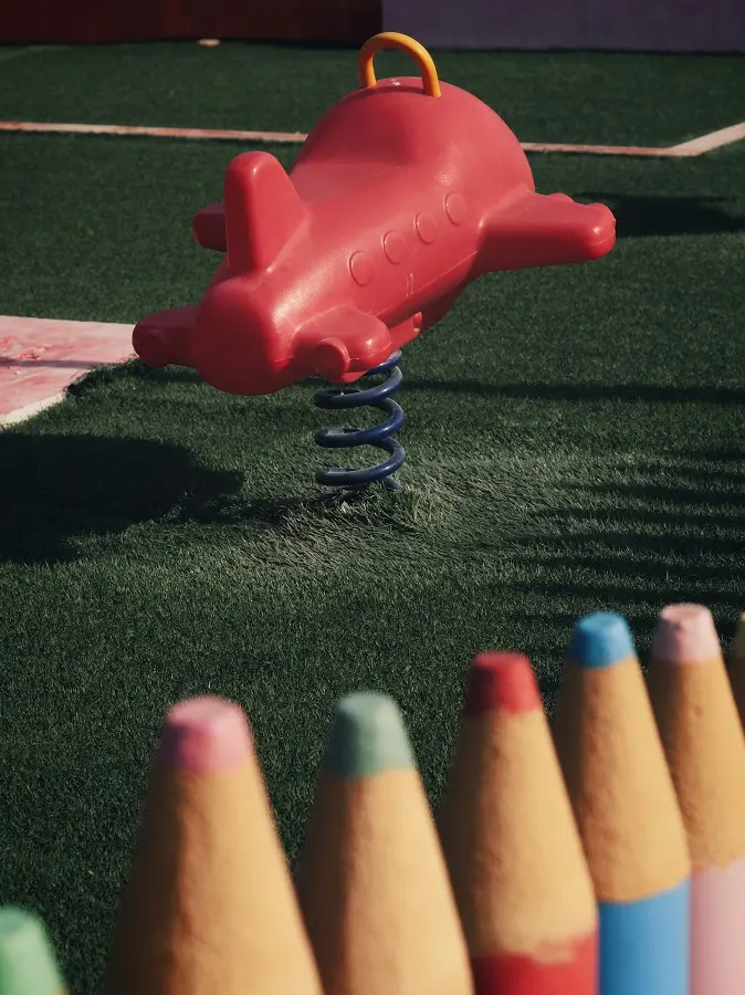 A child's playground toy of a red airplane on a spring.