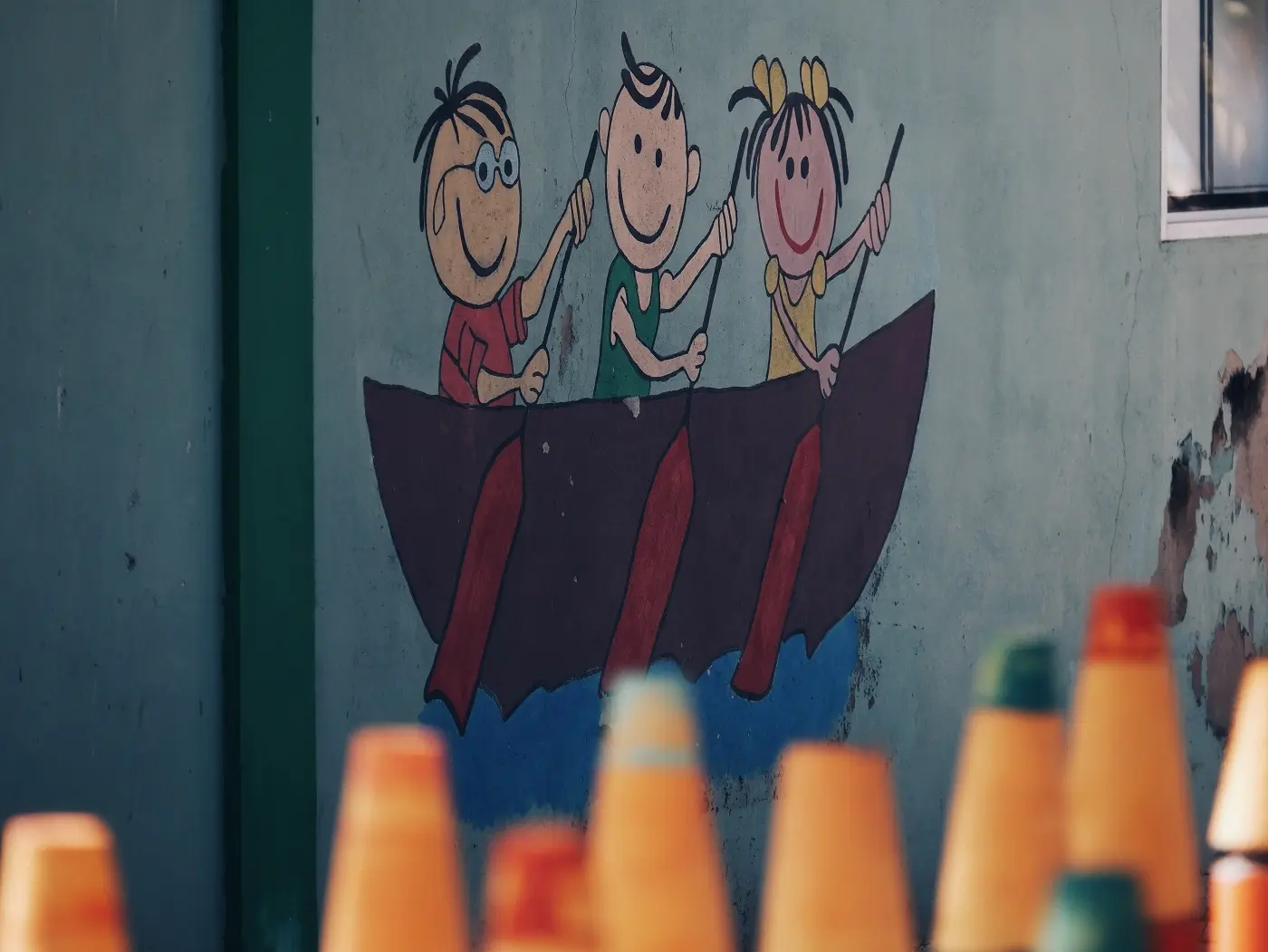 A wall mural on a school in Maafushi of three children in a boat.