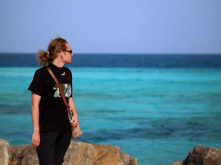 A person looking over the waves from the shoreline of Maafushi, Maldives.