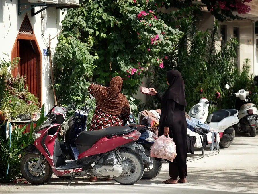 Two ladies with motorbikes shopping on Maafushi in the Maldives.