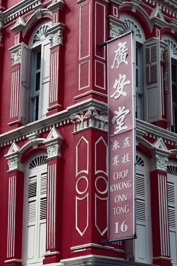 Vibrant red walls and white shutters on a building in Singapore's Chinatown area.