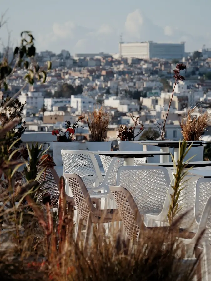 Chairs atop a rooftop with views of the skyline of Tunis in the background.