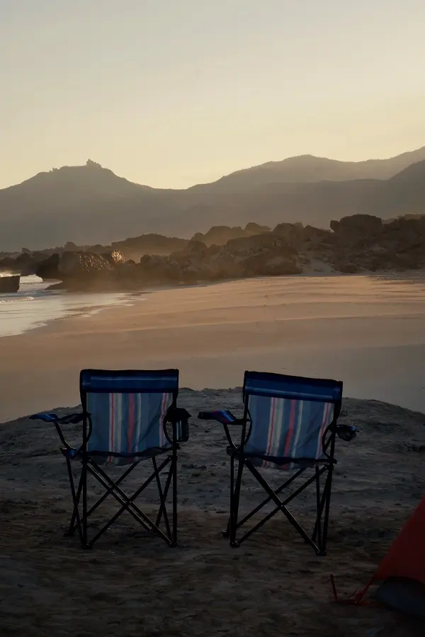 Two camping chairs during sunrise at Fazayah beach in Oman.