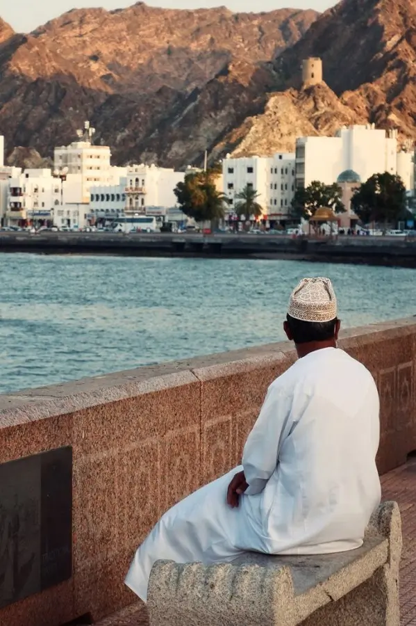 A person sat by the blue waters at the corniche in Mutrah, Muscat.