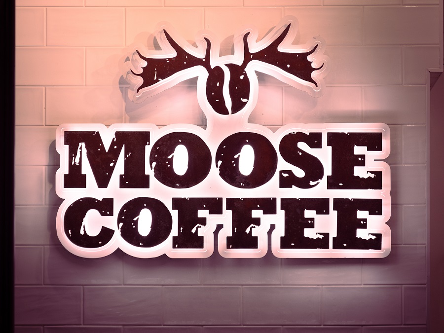 A brightly lit up sign outside a café in Leeds which says 'Moose Coffee'.