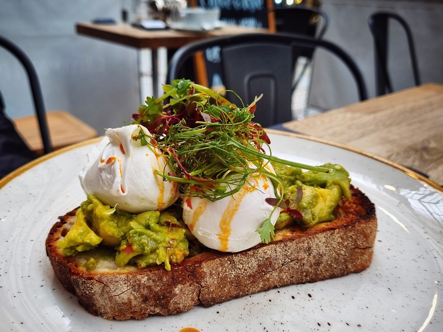 Two poached eggs and smashed avocado on toast on a gold rimmed plate at Olive and Rye, Leeds.