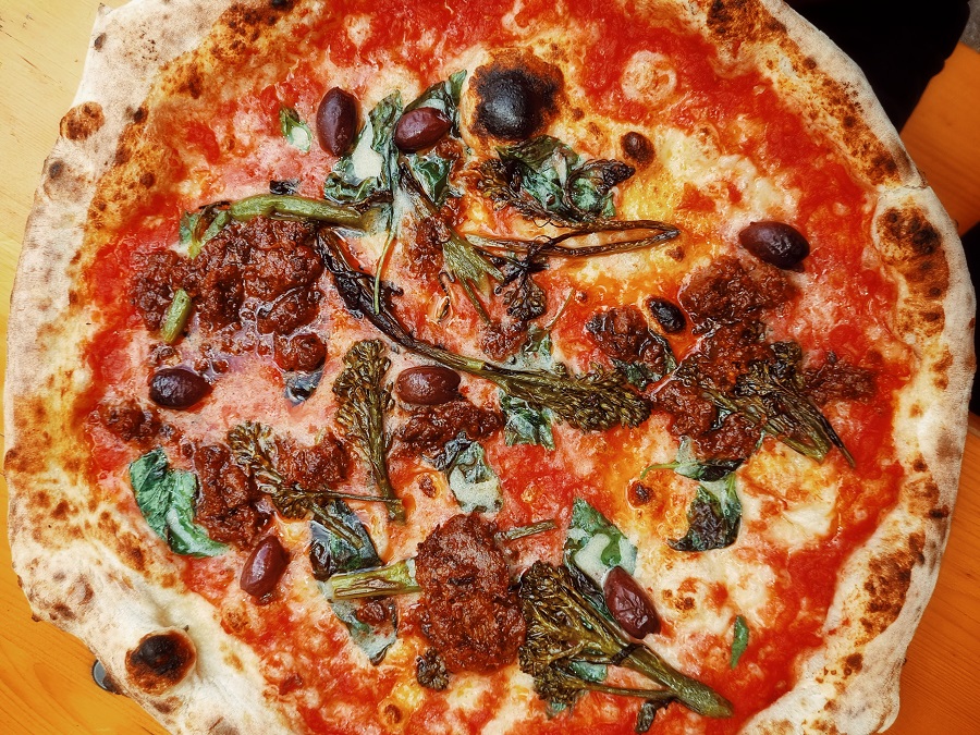 A vegetarian pizza with olives, broccoli and plant-based spiced lamb.