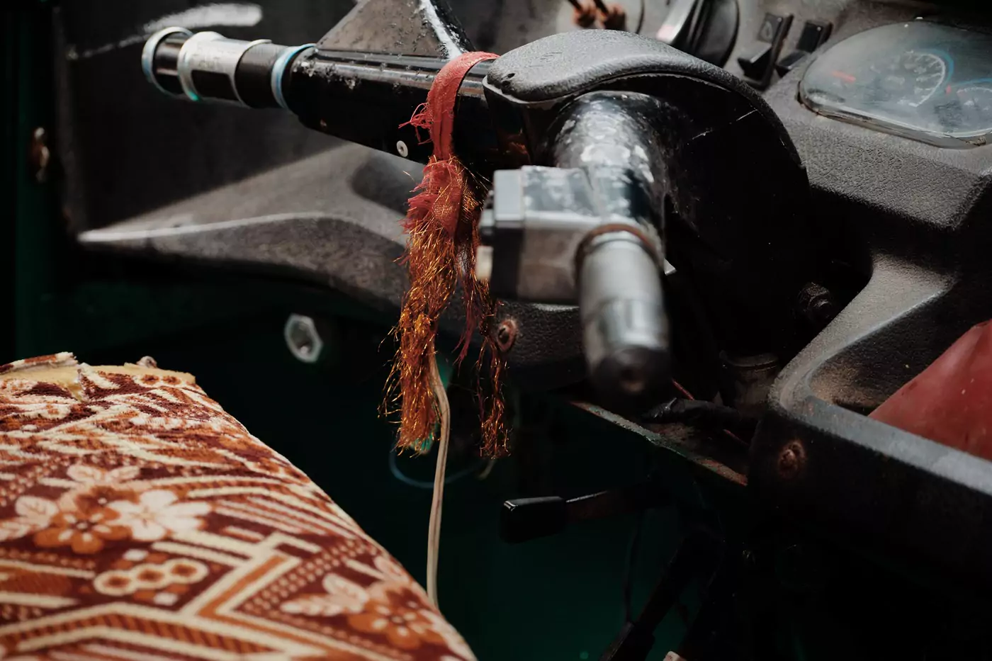 The inside of a tuktuk showing the dashboard and handle.