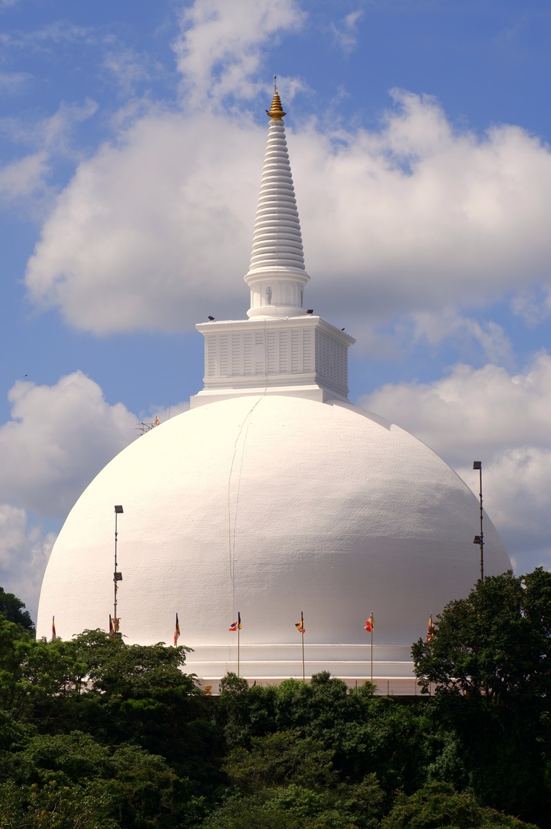 The white Mahaseya Dagoba at Mihintale, surrounded by green trees and flags.