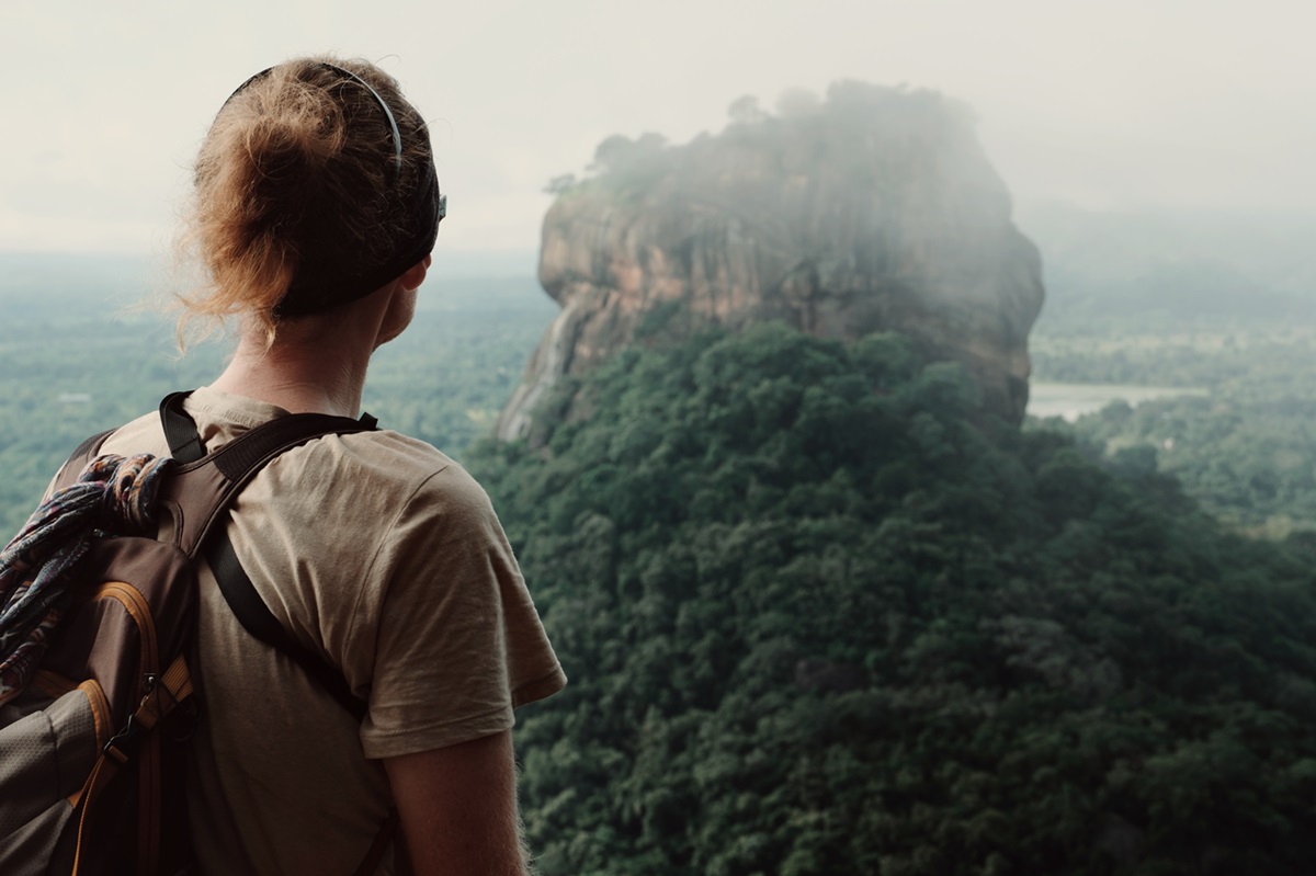 A person looking at the mist rolling in at the summit of the Pidurangala Rock Hike.