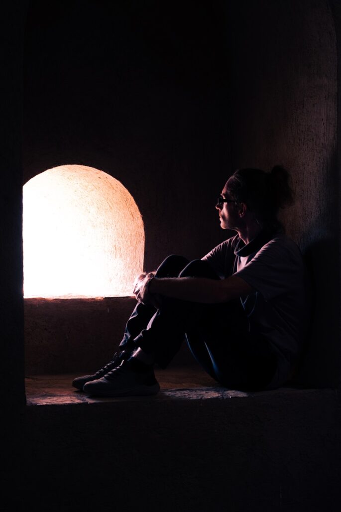 A man sat inside the main cannon turret, lit up by the sunlight outside the fort at Samail.