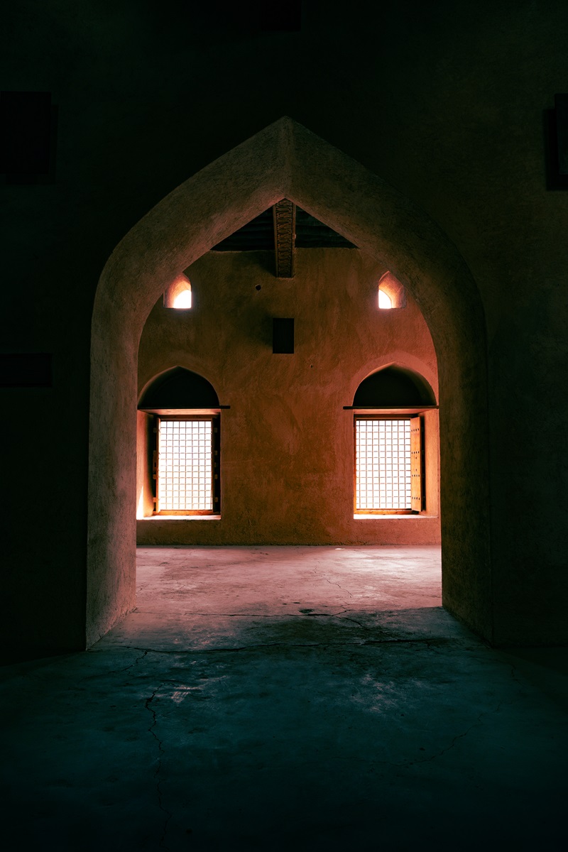 An archway between two rooms lit by external light, inside the Omani fortress at Samail.