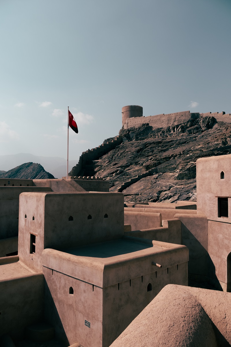 A Oman flag blowing the the wind above an Omani Fortress in Samail, Oman.