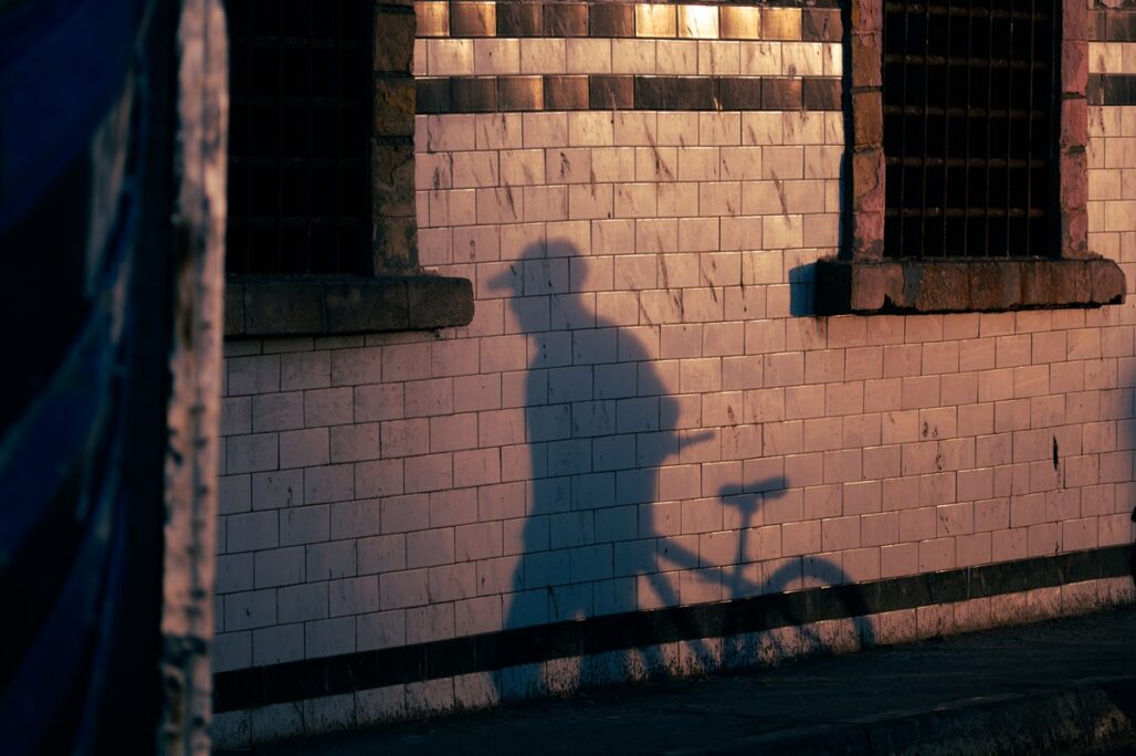 A shadow of a cyclist against white tiled walls in Essaouira, Morocco.