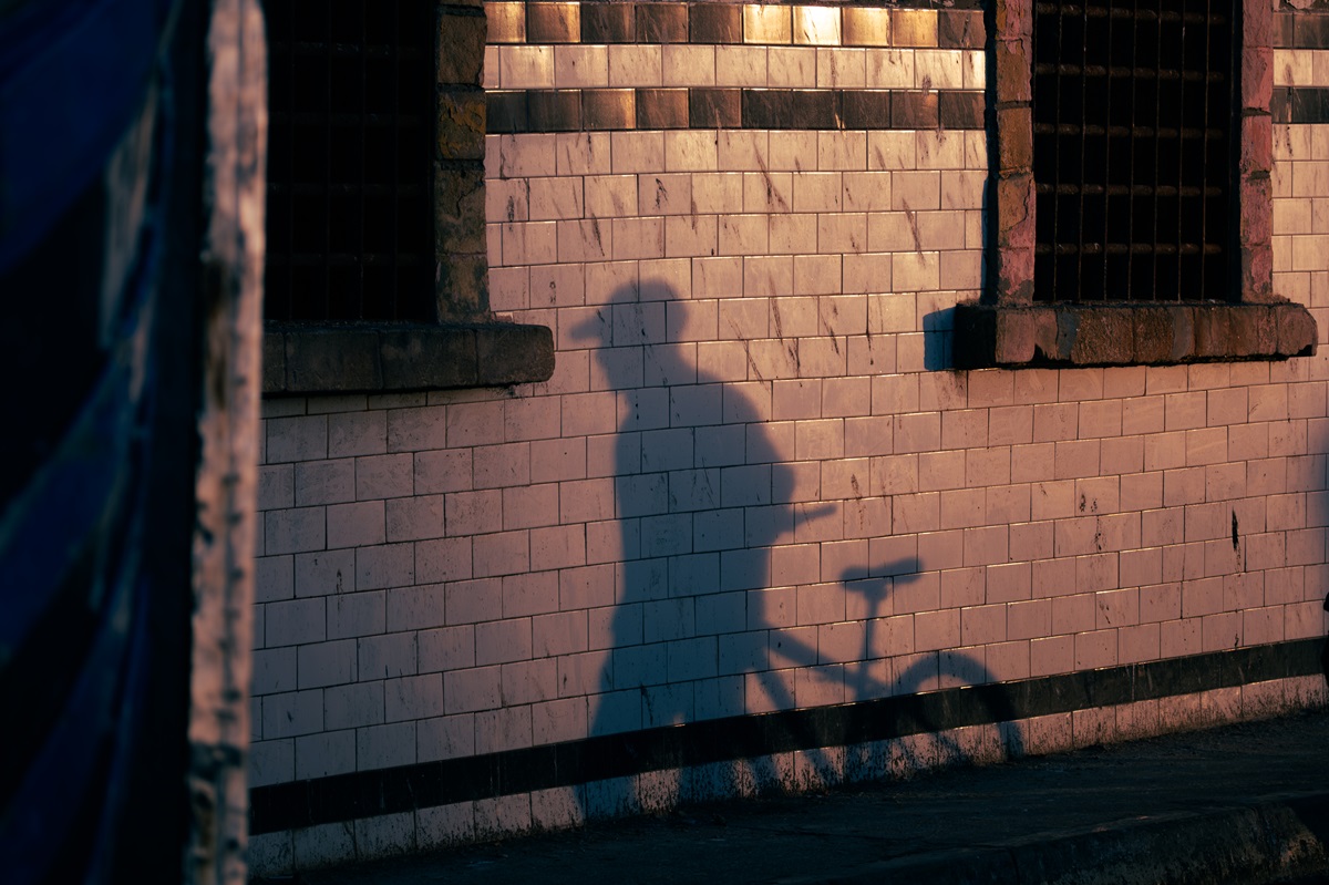 A shadow of a cyclist and their against white tiled walls at sunset in Essaouira, Morocco.