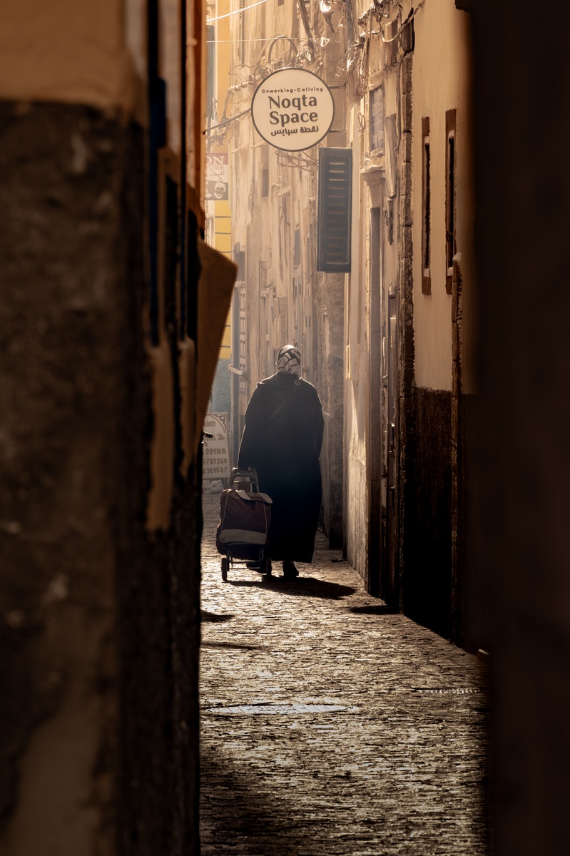 A person with their shopping walking through the narrow cobbled streets of Essaouira's medina.