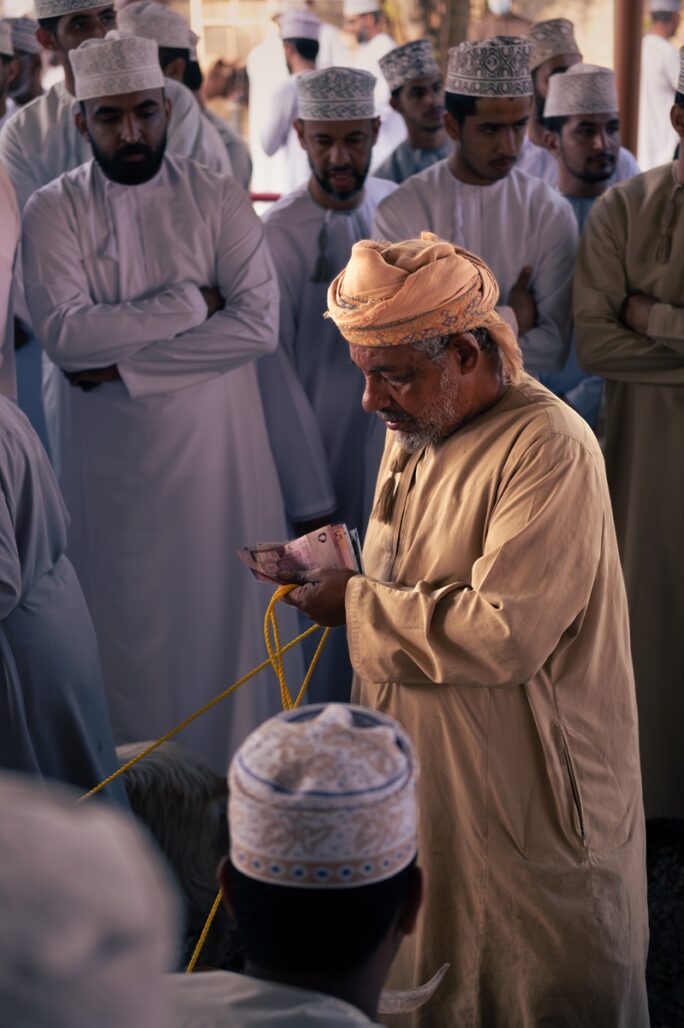 A person in the process of paying with Omani rials at the Nizwa goat market.