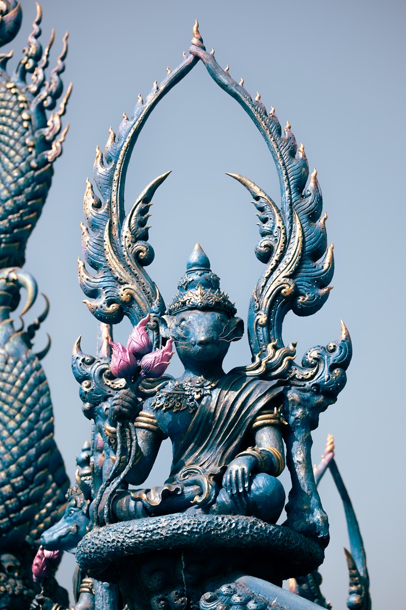 A part rat, part human statue sitting down at the Blue Temple in Chiang Rai.