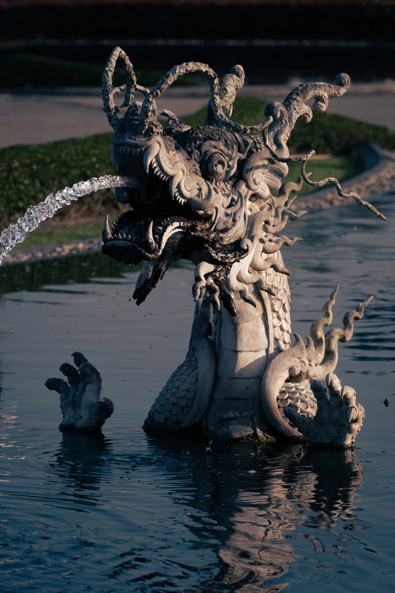 A dragon shaped water feature with water coming from its mouth at the White Temple, Thailand