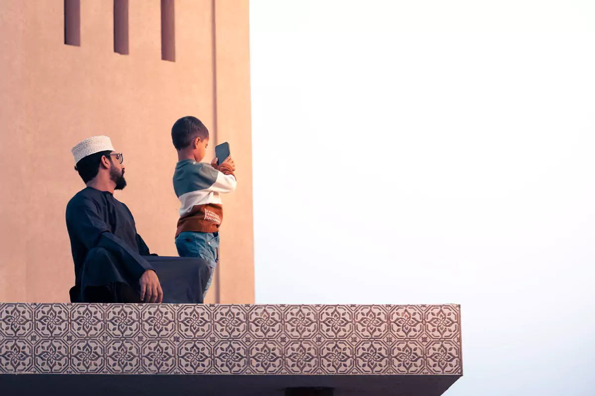 A child taking pictures on their parent's mobile phone at the goat market in Nizwa, Oman.