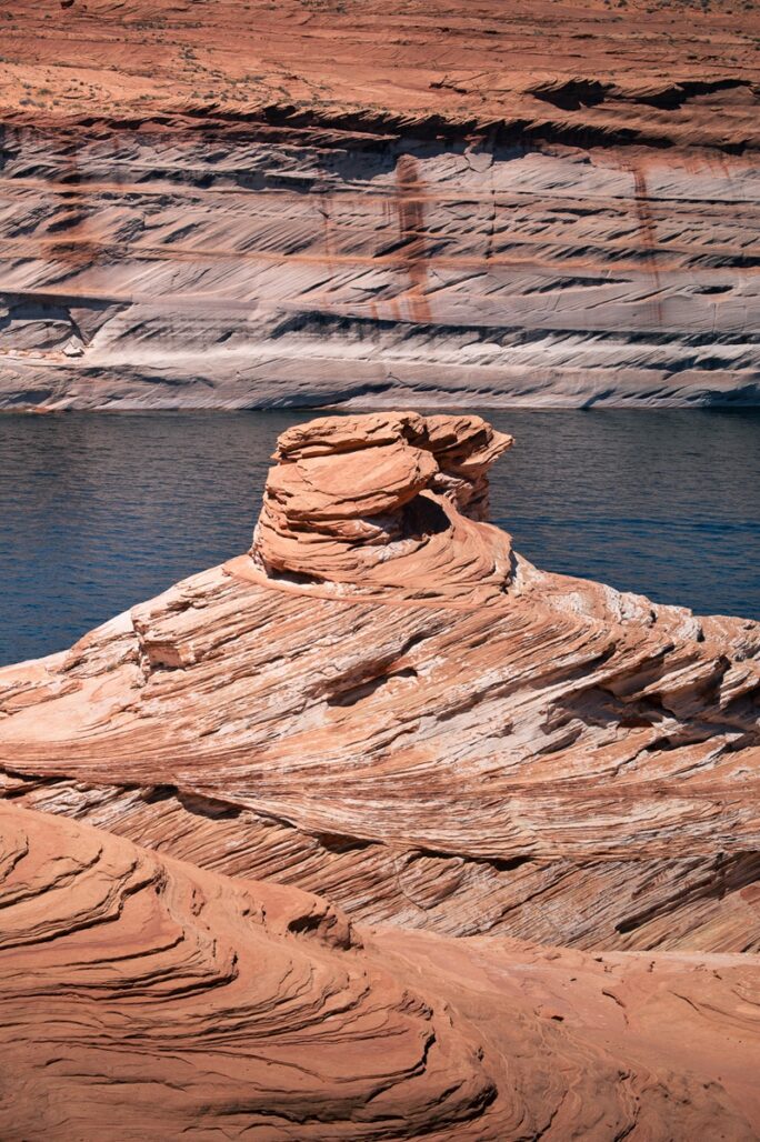 Swirling orange sandstone rock formation along the banks of Lake Powell.