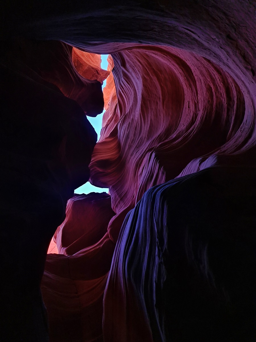 Looking up at purple tinted walls in a slot canyon in Utah.