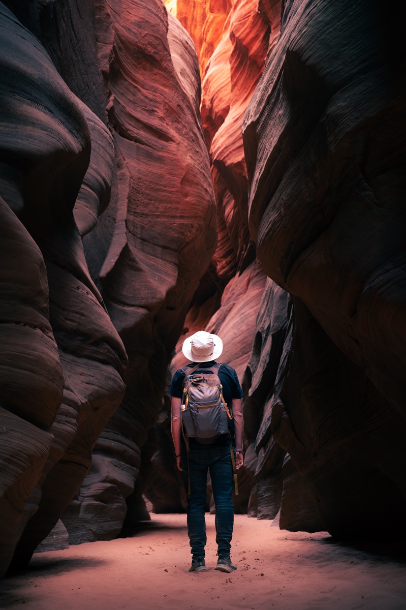 A person looking at light coming in from the top of a slot canyon.