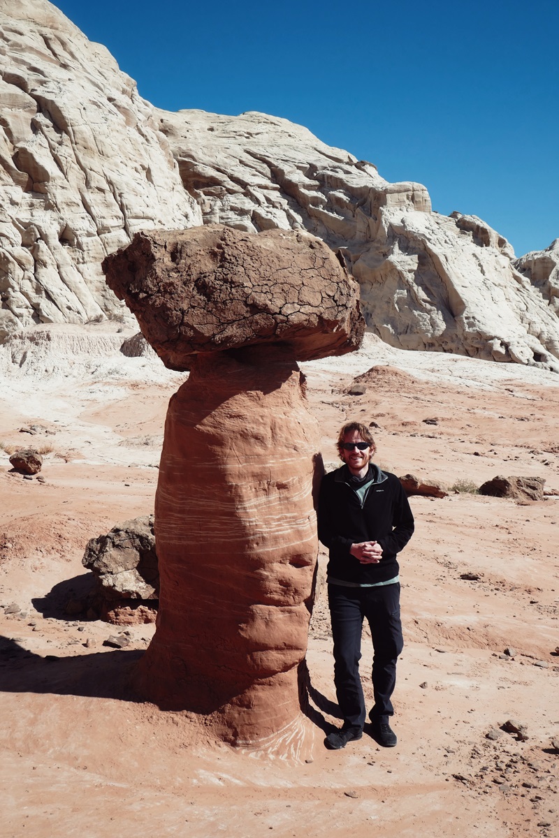 A person standing next to one of the smaller, mushroom shaped rocks on the Toadstool Hoodoos Trail, Utah.