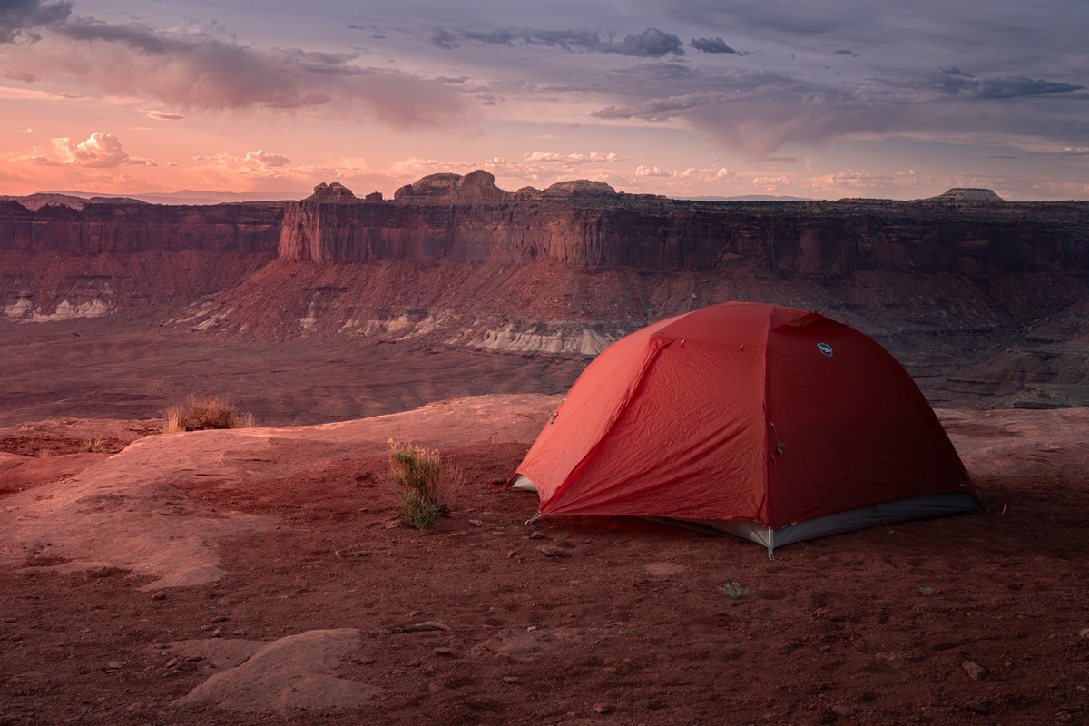 A red tent set up near a ledge at Murphy Point with views of Canyonlands below.