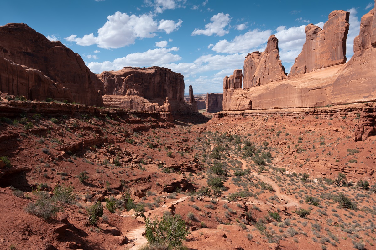 The trail at the Park Avenue Hike in Arches National park with unique rock formations in the background.